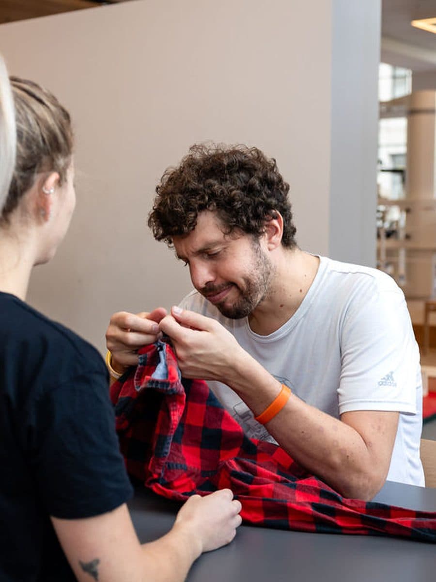 Paziente che si esercita ad abbottonare una camicia con una terapista da Nextherapy