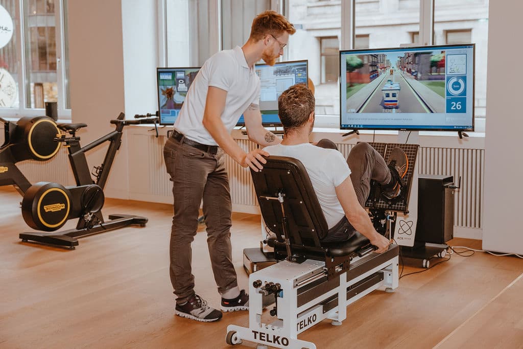 Un patient adulte s’entraîne sur le Telko avec un thérapeute chez Nextherapy