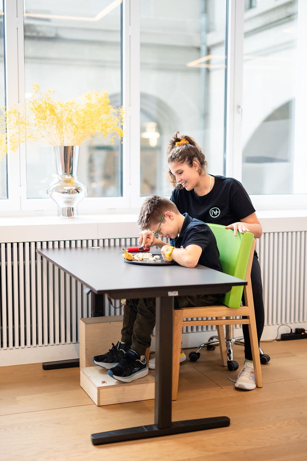 Una terapeuta ocupacional practica comer con cuchillo y tenedor con un niño en Nextherapy