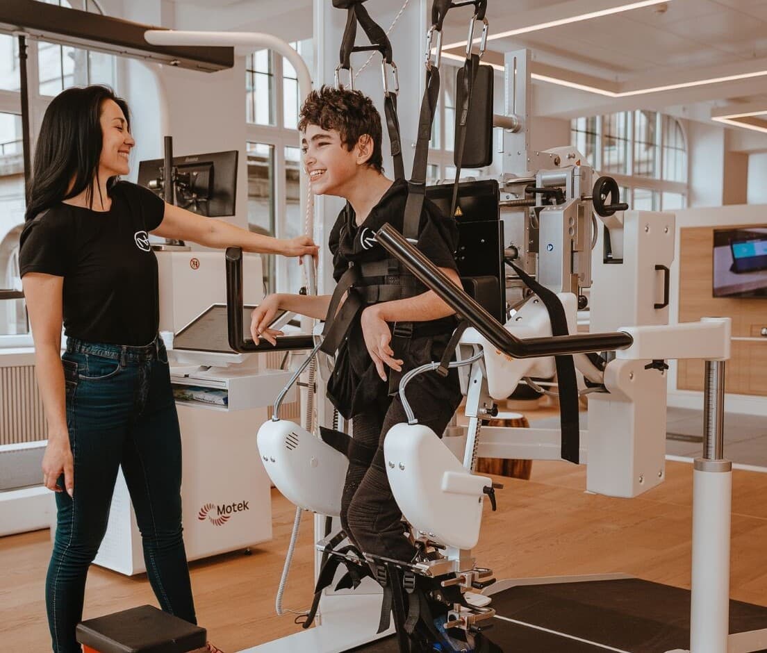 Kind beim robotergestützten Gangtraining im Lokomat Pediatric, begleitet von einer Therapeutin